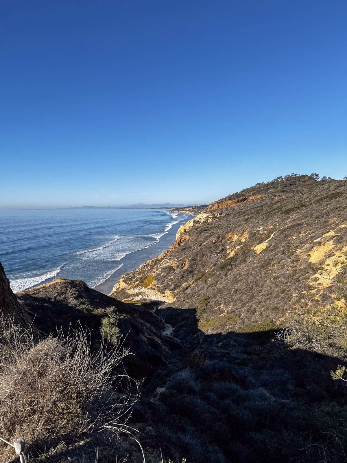 A shadowed sandstone bluff above the surf, looking north