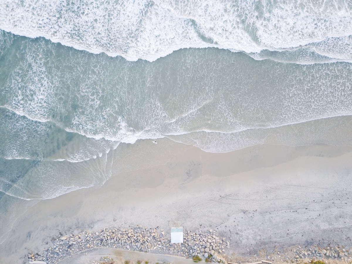 Aerial view of surf washing onto a wide sandy beach
